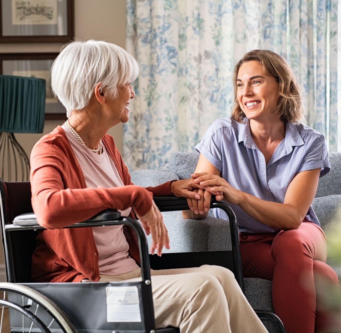 Caregiver talking warmly with an elderly woman in a wheelchair.