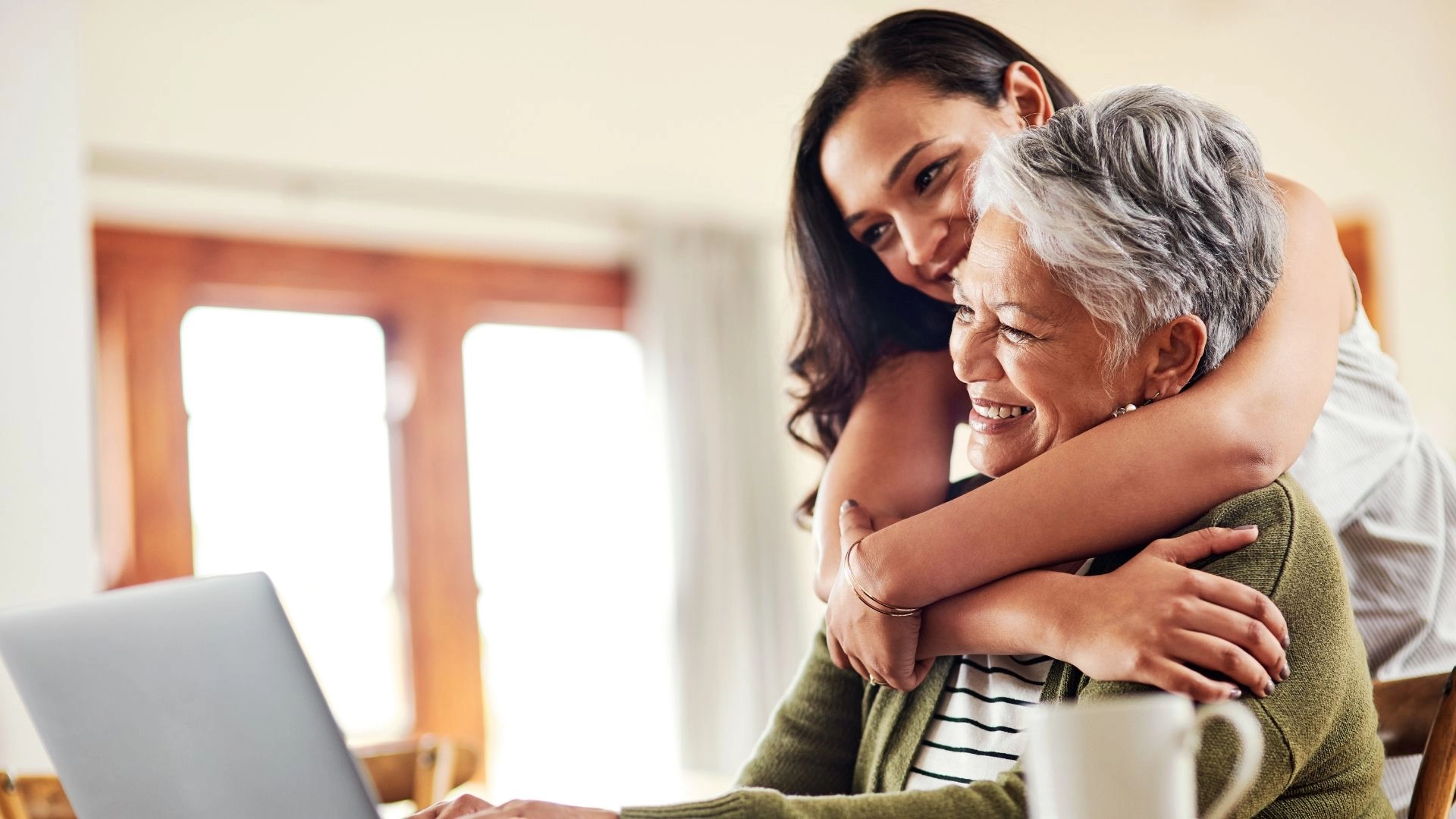Young woman lovingly hugging an older woman at home, showing emotional support and quality senior home care in Brawley.