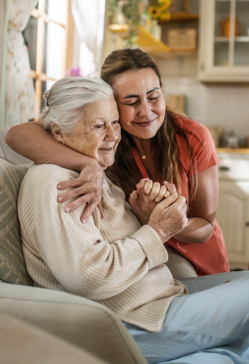 Caregiver hugging an older woman in a kitchen setting, offering comfort and reassurance.