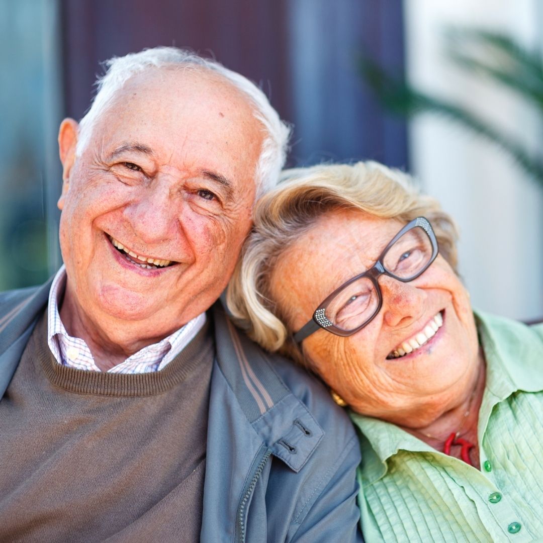 Happy Senior Couple Enjoying Quality Time Together Smiling senior couple sitting closely together outdoors, representing healthy aging and supportive senior home care services.